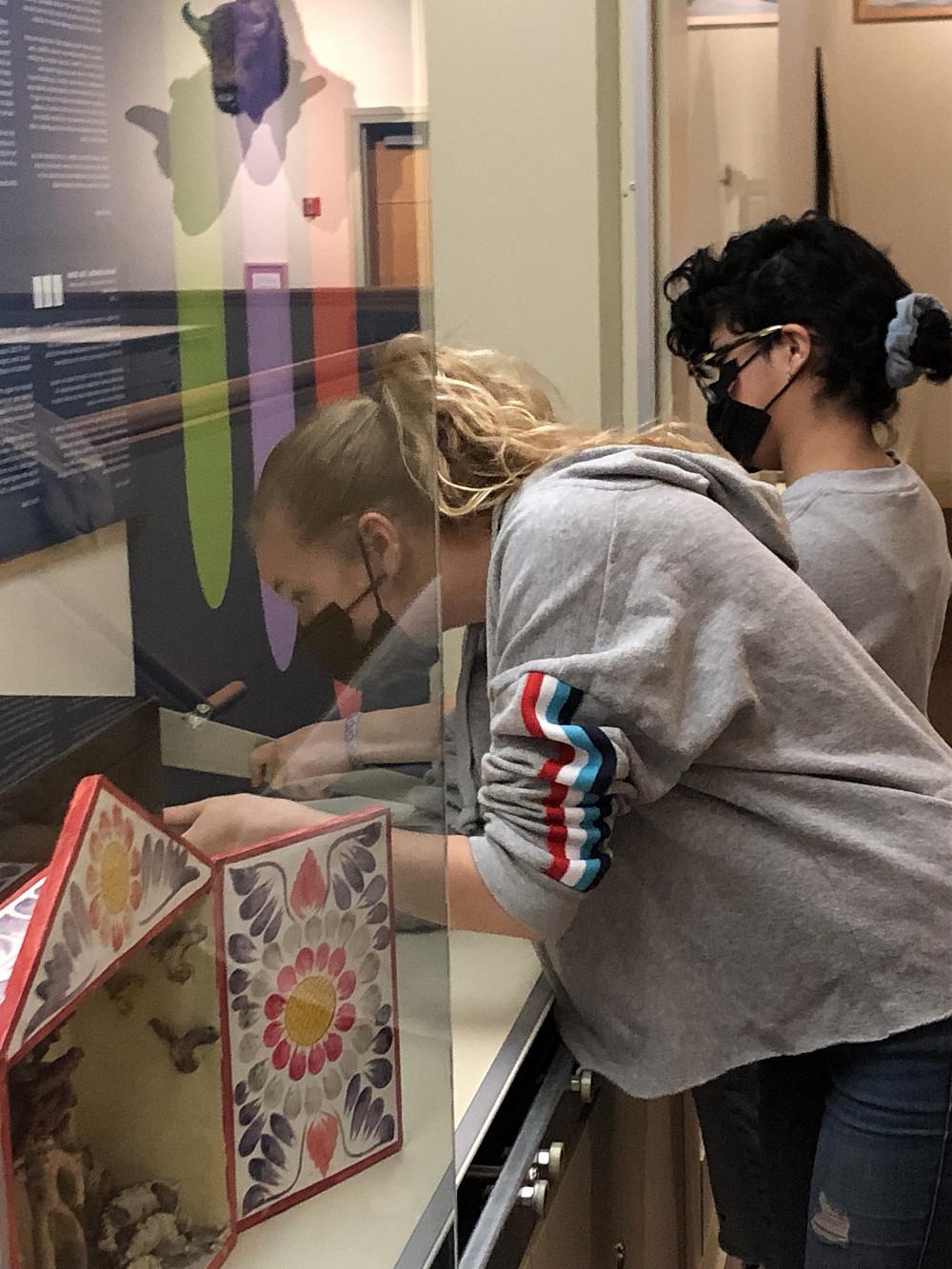 Tiffany Toledo and Dahlia Shearer set up their objects for an exhibit for Sylvia Lopez's class Health in the Spanish-speaking World.